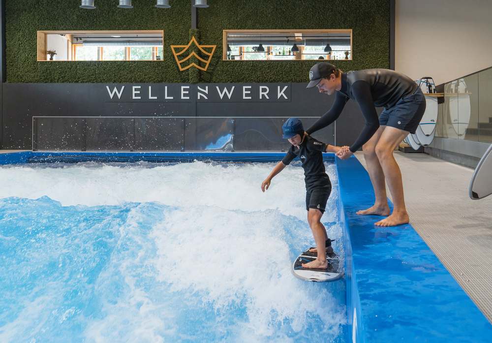 Child stands with a support bar for the first time on the standing wave at Wellenwerk Berlin