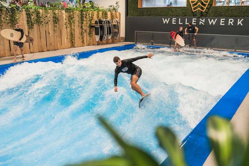 Surfer riding the wave at full speed, hall in the background